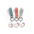 Three leather strap photo keychains with cartoon artwork on acrylic discs